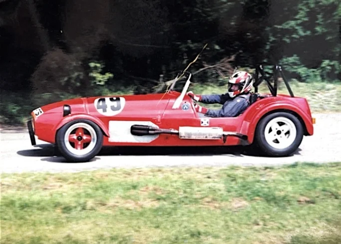 Red open-wheel sports car number 49 on hillclimb stage